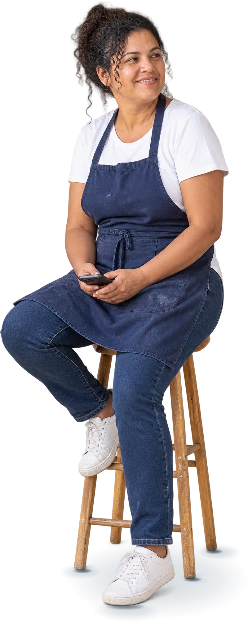 Dona de padaria sentada num banquinho de madeira, segurando o celular, com expressão tranquila